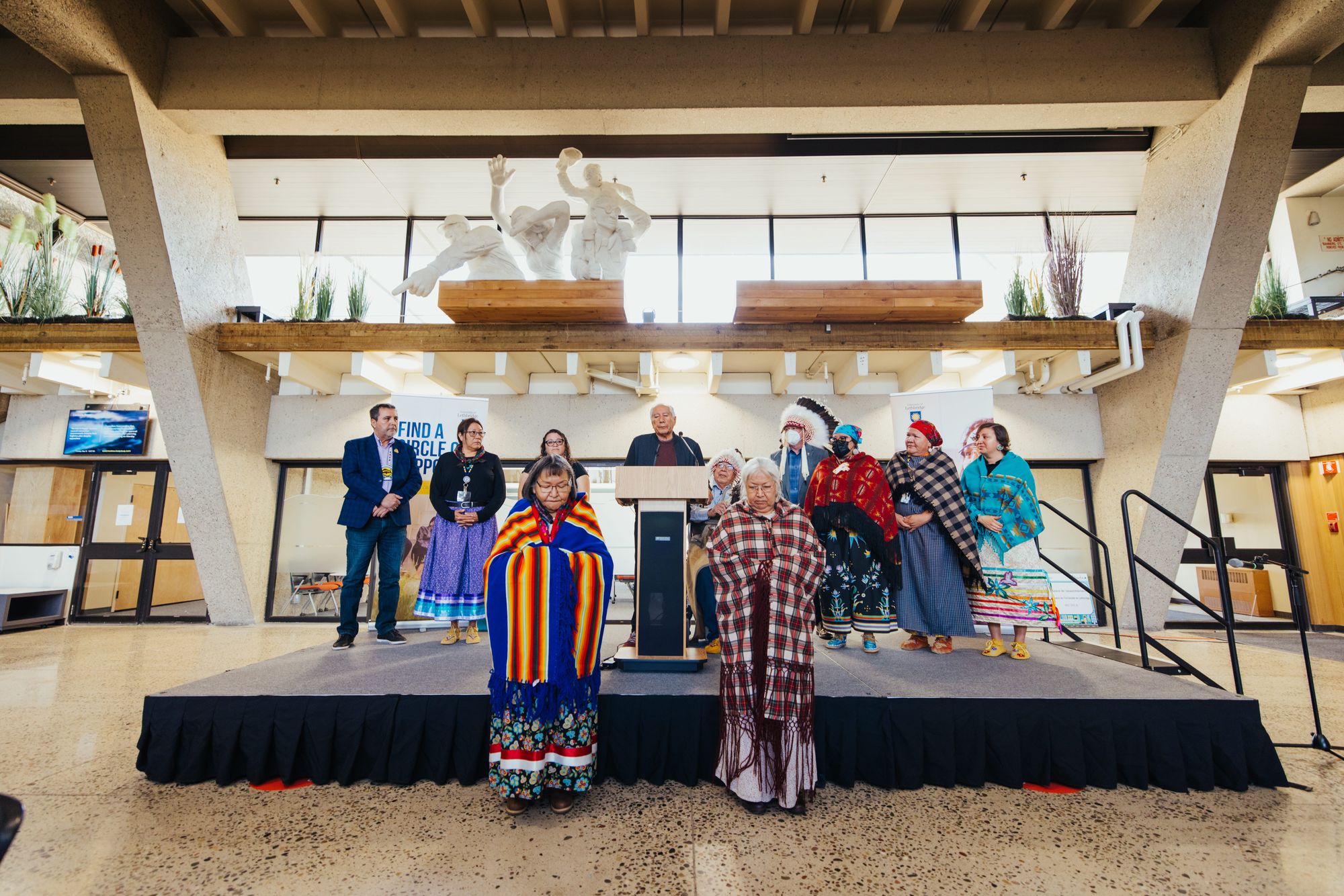 Blackfoot Elders and Navigators bowing their heads in prayer on a podium.