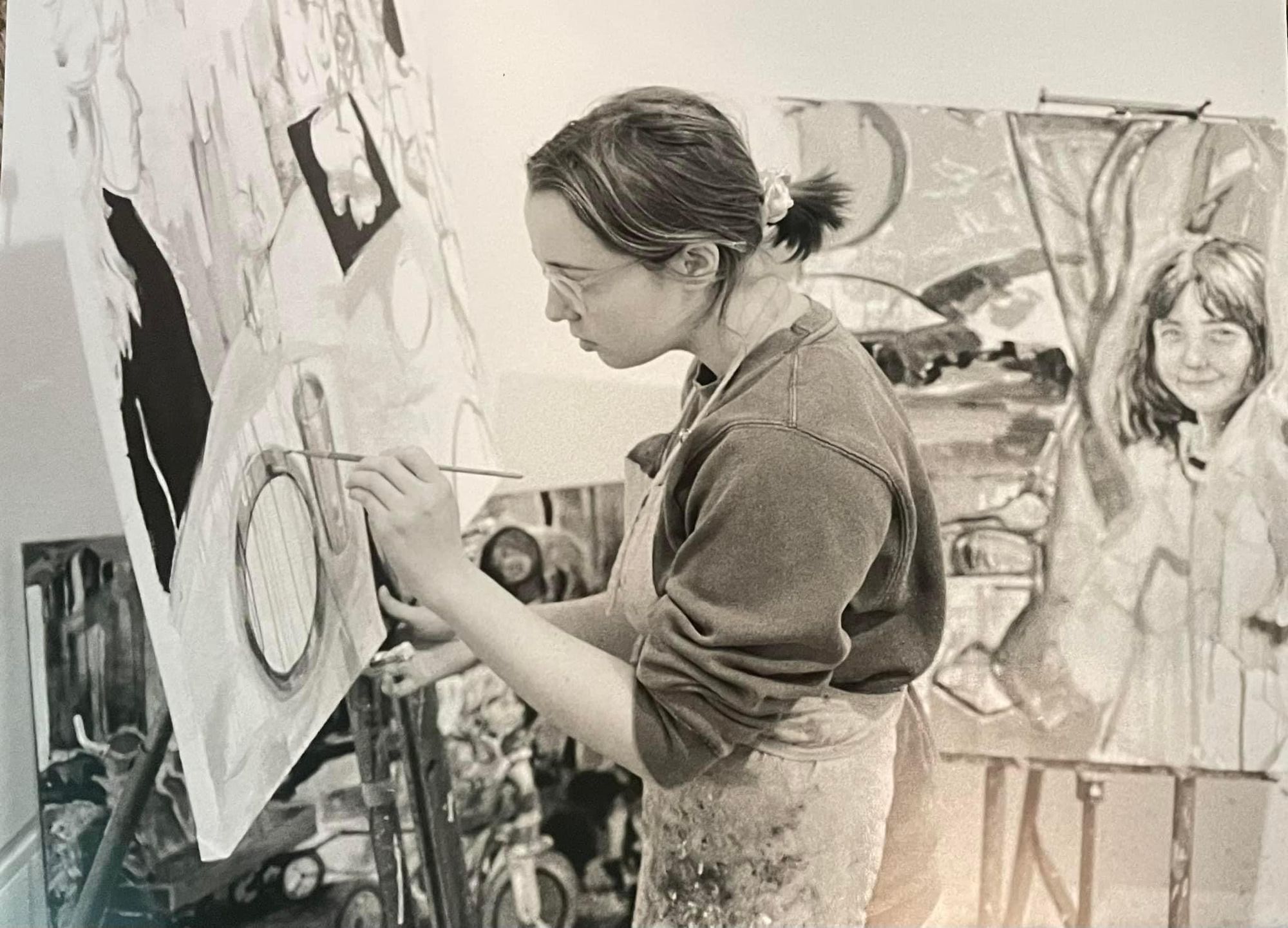 Artist wearing apron painting at an easel