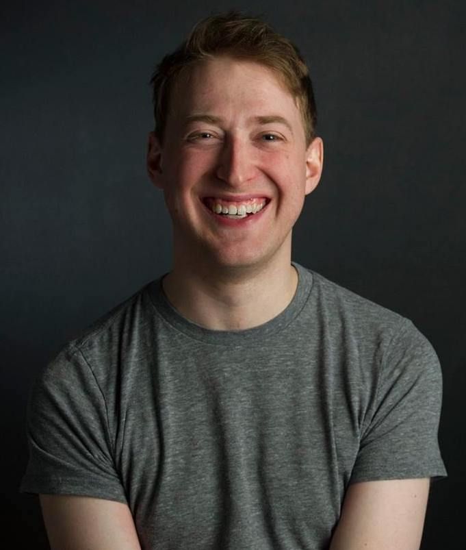 James Wade wearing a grey t-shirt and smiling at the camera.