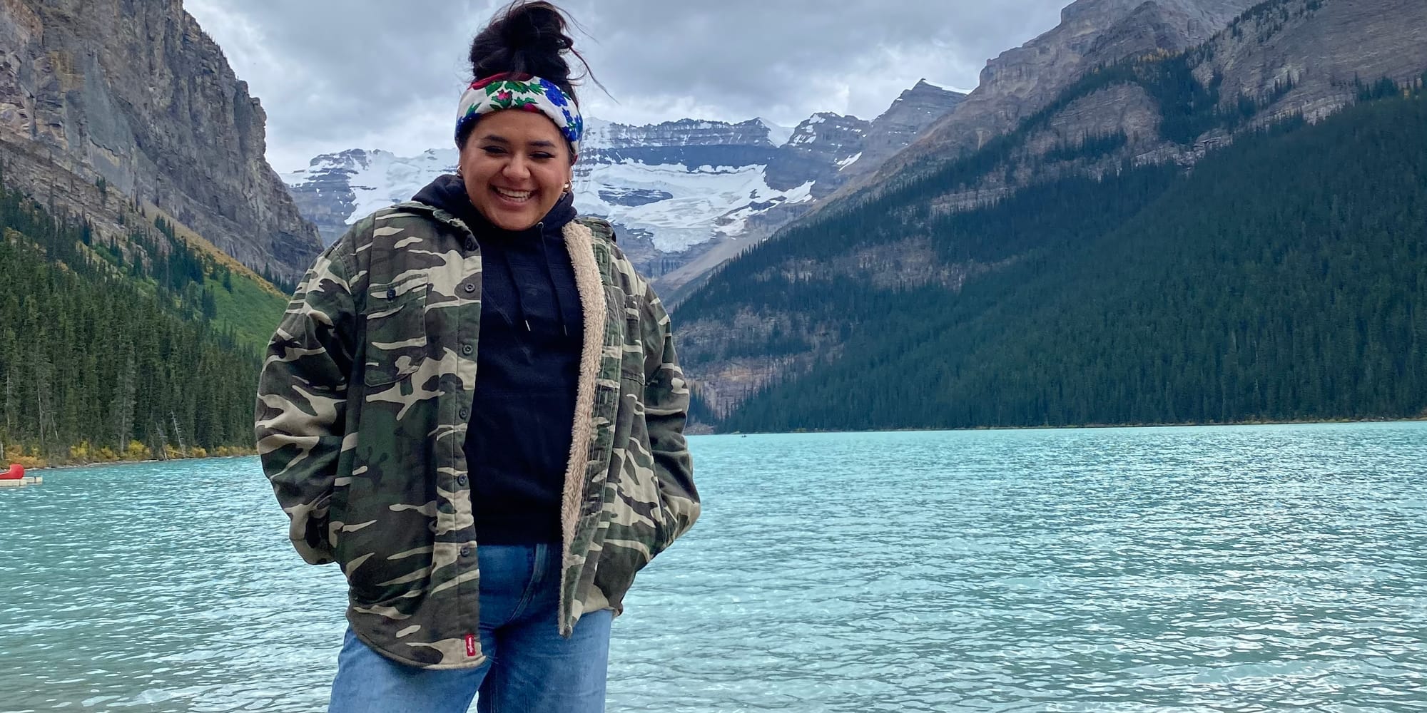 Kirsten Lindley standing on shore of Waterton Lake with Rocky Mountains in background